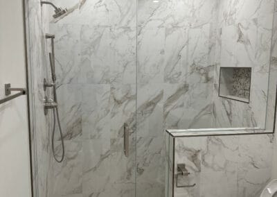 Beautiful marble shower featured in home remodel with custom trip and flooring