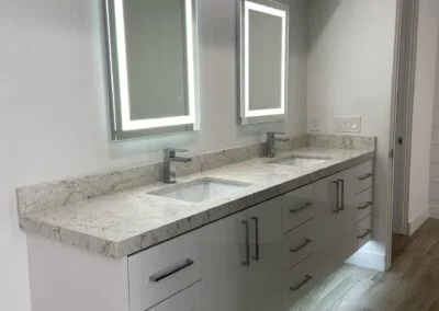 Home bathroom remodel featuring custom lighting fixtures, stone countertops, and upgraded flooring.