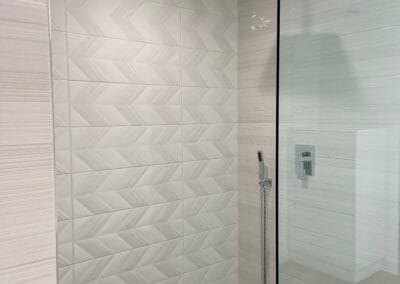 Custom rainfall style shower renovation with dark floor stone tile and white wall tile, open shower with glass.