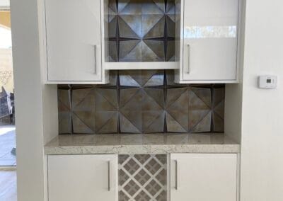 Custom kitchen renovation featuring designer backsplash and stone countertops with modern white cabinets