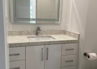 Beautiful bathroom renovation featuring custom lighting options and stone countertops with modern flooring and cabinets.