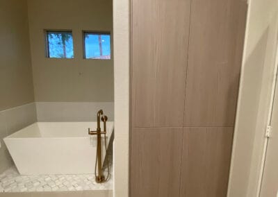 Bathroom remodel featuring custom square tub with gold faucet and walnut cabinets