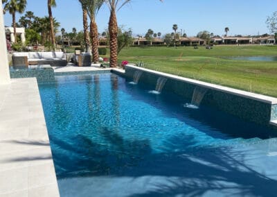 Beautiful backyard with stunning blue pool nested within a country club. Palm trees and golf course in background.