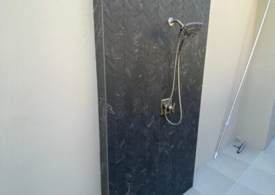 Image features custom outdoor shower design made of black stone.