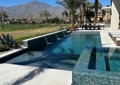 Modern pool and spa design features hues of blue and sits on a country club golf course.