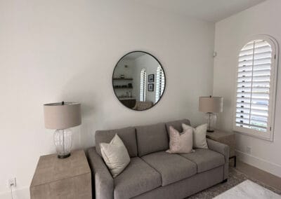 Living space with large designer mirror and custom blinds