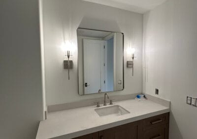 Home remodel bathroom renovation featuring rounded square mirrors and sinks. White countertops against modern dark wood cabinets.