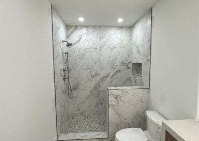 Beautiful marble shower featured in home remodel with custom trip and flooring