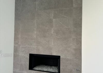 Home renovation featuring beautiful stonework upgrade for fireplace with fireplace glass