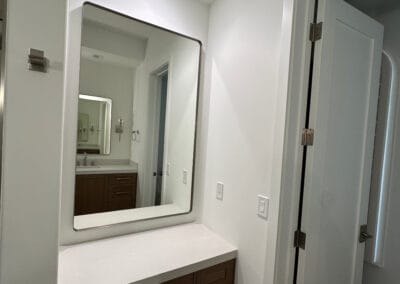 Home remodel bathroom powder room renovation featuring rounded square mirrors and white countertops against modern dark wood cabinets.