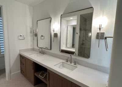 Home remodel bathroom renovation featuring rounded square mirrors and sinks. White countertops against modern dark wood cabinets.