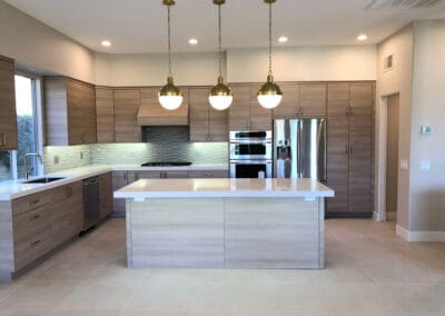 Elegant and modern kitchen design with stylish lighting, wooden finish cabinets, and upgraded countertops, island, and backsplash.