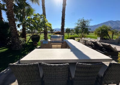 Upgraded custom BBQ with countertop with chairs for guests. Overlooks a country club golf course in the background.