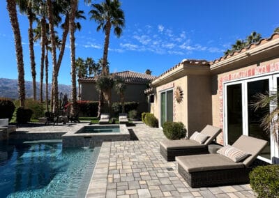 Upgraded modern design pool and patio. Lounge chairs for guests overlooks a country club golf course. A house sits in the background.