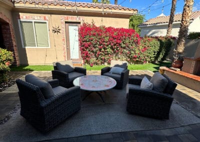 Outdoor furniture staged on top of a rug. Backyard features an upgraded stone patio.