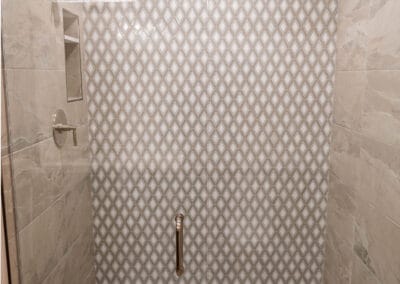 Beautiful shower remodel featuring diamond pattern tile walls adjacent to light stone tile walls and hexagon stone flooring.