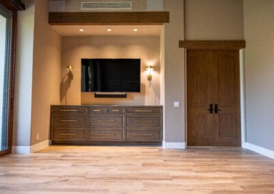 Gorgeous home remodel featuring bedroom with wood floors, and custom ceiling fan. Wood trim accent above window and custom lighting accents. A TV sits above custom wood dressers.