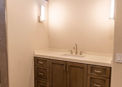 Complete bathroom remodel featuring modern dark wood cabinets, and stone sink, with custom tile flooring with wood and stone hexagon pattern