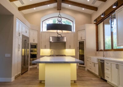 Stunning and elegant home interior design. Beautiful kitchen with upgraded white cabinets, countertops, and backsplash. Wood flooring and accent rafters and lighting.