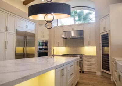 Stunning and elegant home interior design. Beautiful kitchen with upgraded white cabinets, countertops, and backsplash. Wolf stovetop and industrial hood. Custom designer lighting