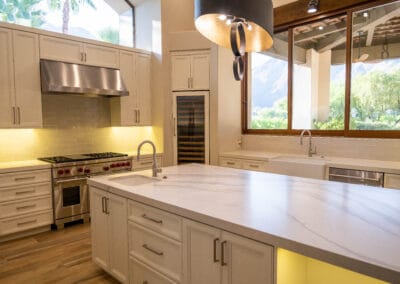 Stunning and elegant home interior design. Beautiful kitchen with upgraded white cabinets, countertops, and backsplash. Wolf stovetop and industrial hood. Custom designer lighting