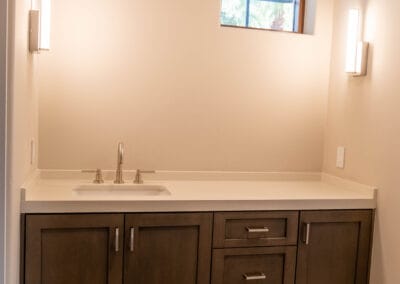 Bathroom remodel featuring dark wood cabinets and white countertop sink with wooden floors